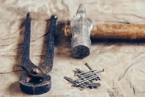 Old rusty pincers, nails and hammer on a wooden background — Stock Photo, Image