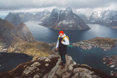 Sarı bir sırt çantası takan gezgin denizin ve dağların arka planında kayaların üzerinde duruyordu. Mesajınız veya tanıtım içeriğiniz için boşluk. Seyahat yaşam tarzı konsepti.