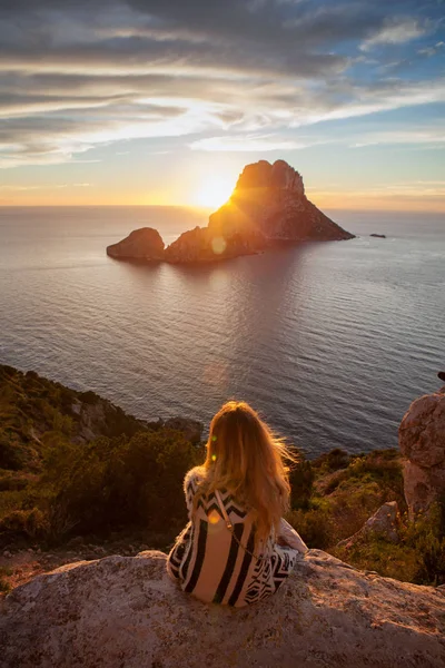 Woman back to the front watching a beautiful sunset at the beach. The beach is called Es Vedra, in Ibiza and belongs to balearic islands, in Spain