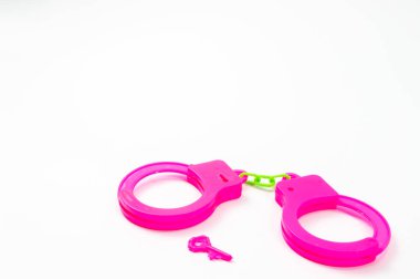 Oyuncak kelepçeler beyaz arka planda pembe..