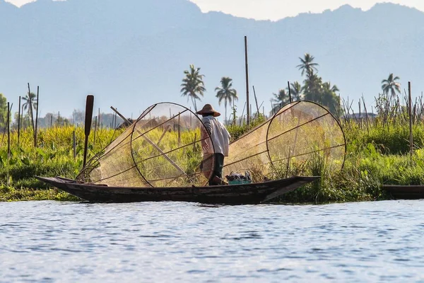 Fisherman rowing boat by leg on Inle Lake, Myanmar.