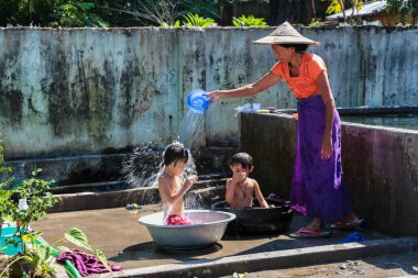 Mandalay, Myanmar - 09 Kasım 2019: Birmanyalı anne Mandalay, Myanmar 'da çocuklarını suyla yıkıyor.
