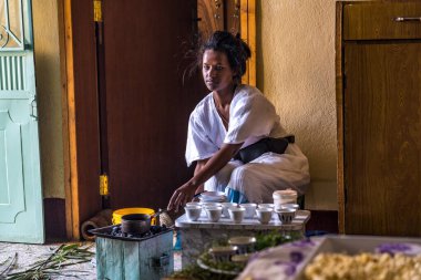 Axum, Etiyopya - 9 Şubat 2020: Geleneksel giysiler içinde genç bir kadın bir kahve seremonisi hazırlıyor. Bu tören Etiyopya kültürünün önemli bir parçasıdır..