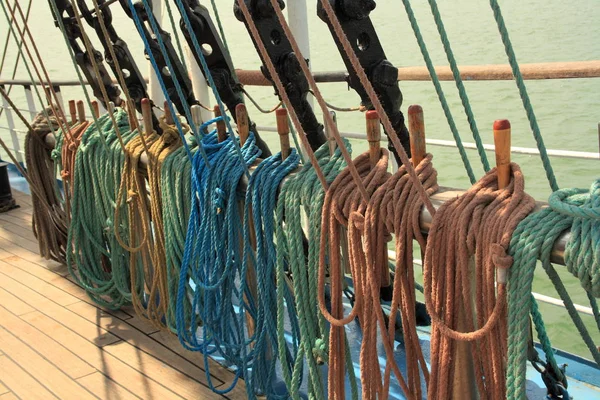 Ship multi-colored ropes on the rails amd wooden deck.