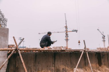 18 Aralık, 2014 Beijing. Vinçler, takeing tuğla ile şehirde bir inşaat alanında bir adam bir