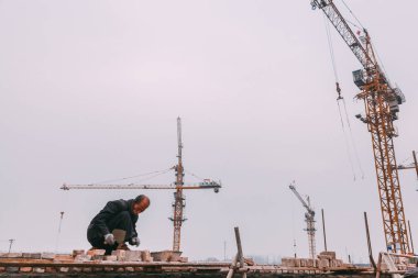 18 Aralık, 2014 Beijing. Vinçler, takeing tuğla ile şehirde bir inşaat alanında bir adam bir