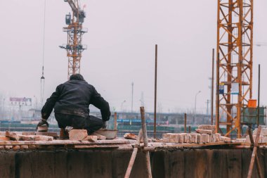 18 Aralık, 2014 Beijing. Vinçler, takeing tuğla ile şehirde bir inşaat alanında bir adam bir