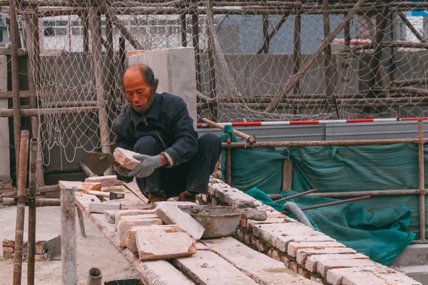 18 Aralık, 2014 Beijing. Vinçler, takeing tuğla ile şehirde bir inşaat alanında bir adam bir