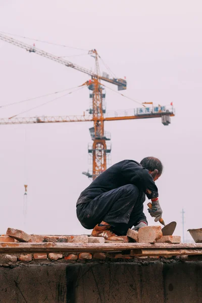 18 Aralık, 2014 Beijing. Vinçler, takeing tuğla ile şehirde bir inşaat alanında bir adam bir