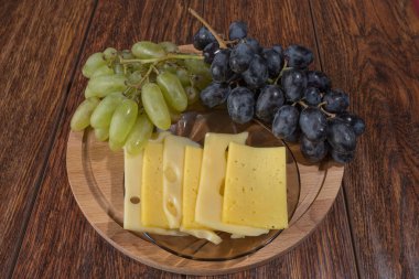 Yuvarlak bir tahtada peynir ve üzüm dilimleme