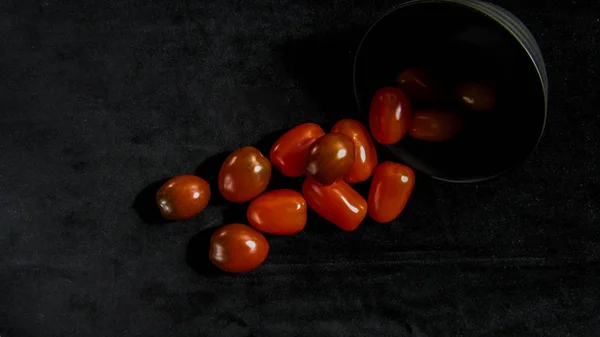 red brown and yellow cherry tomatoes lie near the black plate