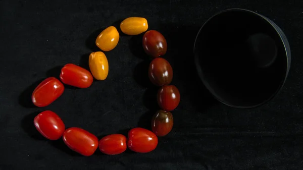 red brown and yellow cherry tomatoes lie near the black plate