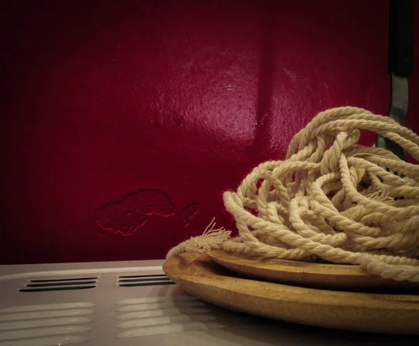 ロープはパスタのビデオの木製の版にあり フォークはそれに挿入される 赤い壁に対して — ストック写真