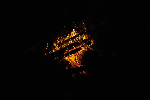 明亮的橙色语言的火在木原在夜间 木材着火 篝火在晚上 美丽的火焰在黑色的背景 火在黑色背景 烧木头 美丽的火纹理 篝火的质地 — 图库照片