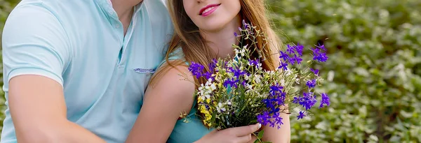 Pareja enamorada en un campo con un ramo — Foto de Stock