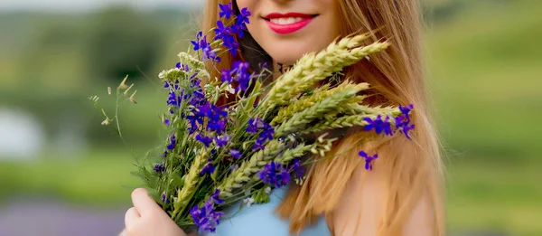 Meisje in de natuur met een boeket wilde bloemen — Stockfoto