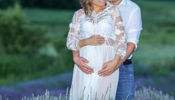 Casal esperando pelo bebê descansando em um campo de lavanda — Fotografia de Stock