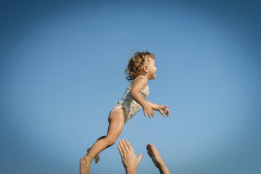 küçük kız havada uçar ve babasının elleri