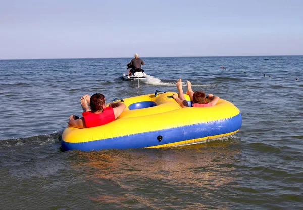As pessoas relaxam no mar e montam um tablet inflável de água — Fotografia de Stock