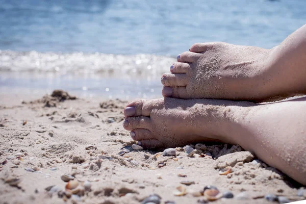 Ноги на песке против синего моря — стоковое фото