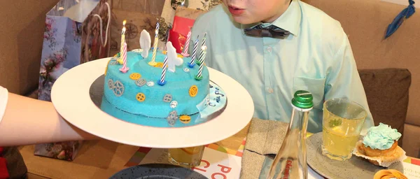 De verjaardag jongen blaast de kaarsen op zijn taart in een café — Stockfoto