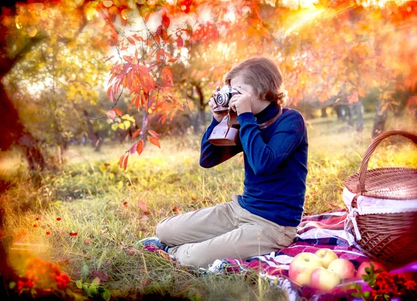 Menino tira fotos em uma câmera rara em um belo parque de outono — Fotografia de Stock