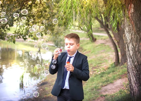 School jongen jongen blazen zeepbellen in de natuur — Stockfoto