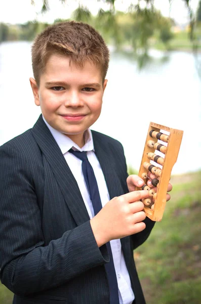 School jongen houdt Abacus in zijn handen en denkt — Stockfoto