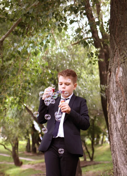 School jongen blazen zeepbellen buitenshuis — Stockfoto