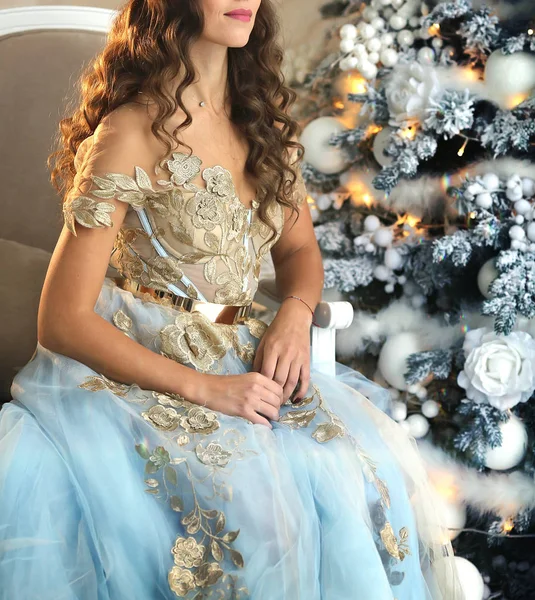 크리스마스 트리 옆에 앉아 아름다운 드레스에 고급스러운 소녀 — 스톡 사진