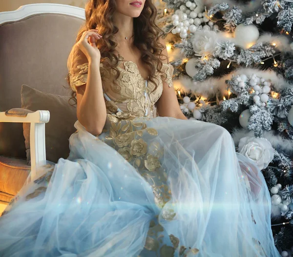Luxusní dívka v krásných šatech, které sedí vedle vánočního stromu — Stock fotografie