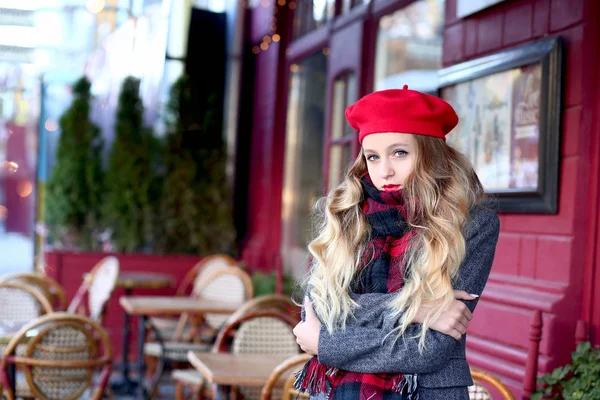 Het meisje in de rode baret bevroor en knuffels zichzelf met haar handen — Stockfoto