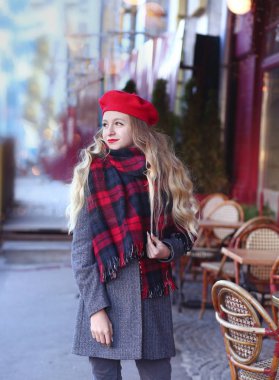 gri bir ceket ve uzun bukleler ile kırmızı bir bere bir gülümseme ile kız