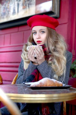 kırmızı bere genç ve ihale kız bir masada oturur ve bir sokak kafede kahve içiyor