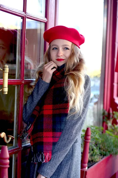 Giovane ragazza in un berretto rosso in un caffè sulla strada — Foto Stock