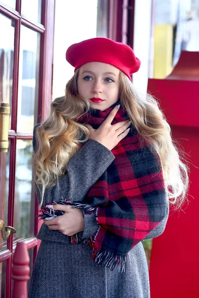 Giovane ragazza in un berretto rosso in un caffè sulla strada — Foto Stock