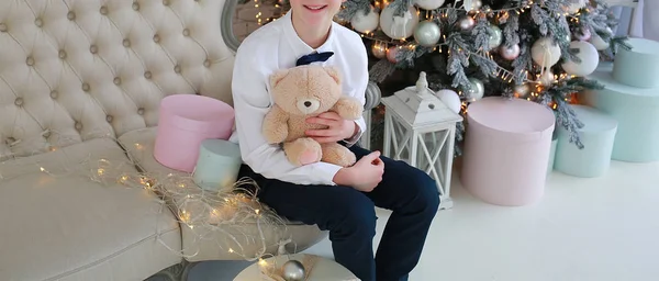 Chlapec s krabicí a medvědem sedí na novoroční pohovce — Stock fotografie