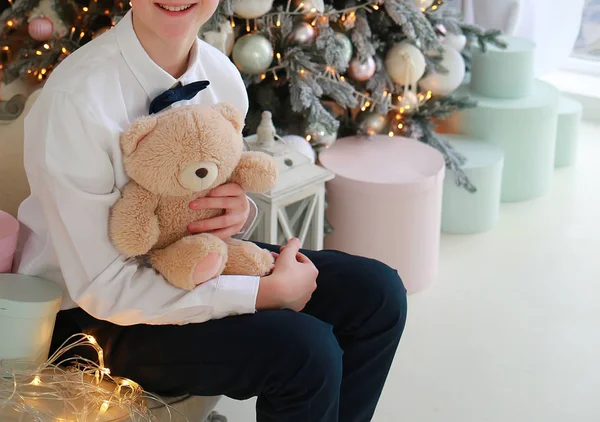 Ragazzo con una scatola e un orso siede su un divano di Capodanno — Foto Stock