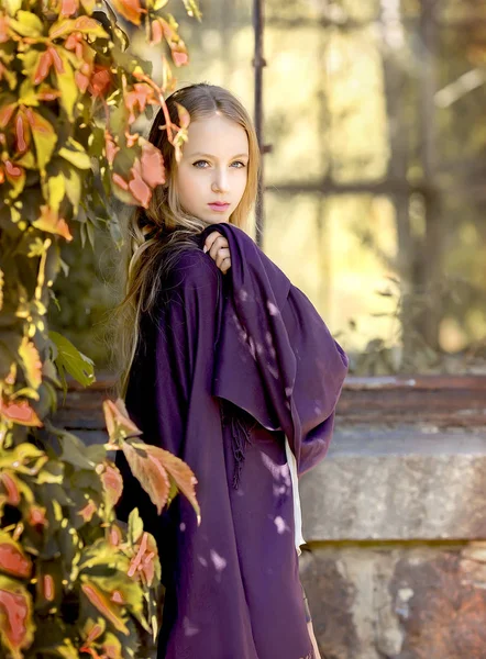 Jong meisje in de natuur in lila op de achtergrond van de greenhous — Stockfoto