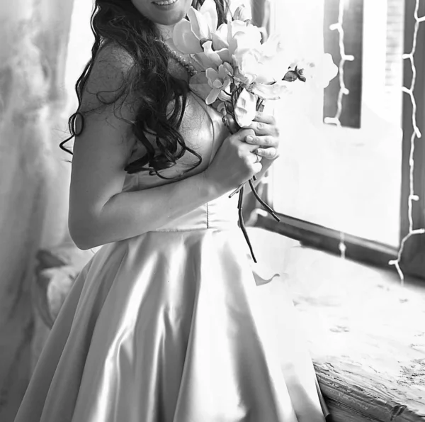Jovem mulher em um vestido lilás com um buquê perto da janela — Fotografia de Stock
