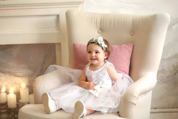 Linda menina em um vestido branco com um pente pequeno senta-se — Fotografia de Stock