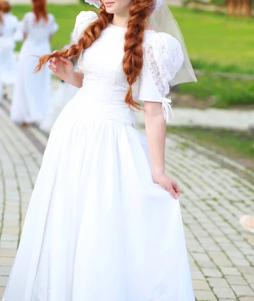 Mooi meisje in een witte jurk met rode vlechten op de natuur in het park — Stockfoto