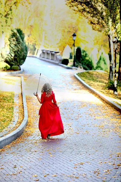 Bela mulher em um vestido vermelho caminha com um guarda-chuva no outono — Fotografia de Stock