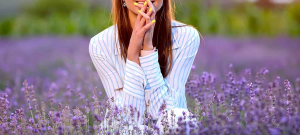 ラベンダー畑に座っていると 明るい黄色のマニキュアの笑顔の若い女の子 ラベンダーと美しい夕日 紫色の花の背景 フラッシュ ボケ効果 美とファッションのコンセプト — ストック写真
