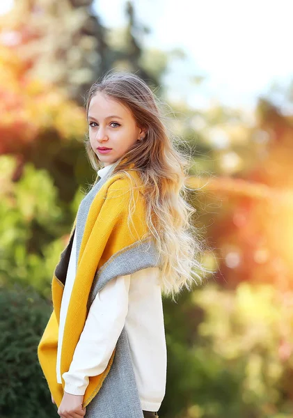 Genç bir kız kameraya bakıyor, sonbahar parkında yürüyor. Sonbahar. Yetişkin çocuklar. Kadın psikolojisi kavramı.