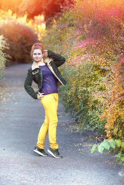 Yaprağın kırmızı ve turuncu yaprakların döküldüğü güzel sonbahar parkı. Mutlu genç bayan sonbahar parkında yürüyor. Sonbahar konsepti