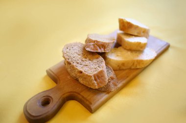 Beyaz ve çavdar ekmeği ahşap bir tabakada parçalara ayrılmış. Yakın plan. Yiyecek.