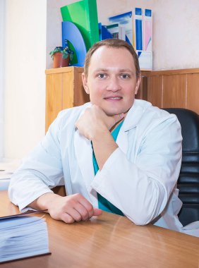 Ofisinde oturup hastalarını bekleyen beyaz önlüklü, gülümseyen beyaz bir doktor terapisti. Tıp ve sağlık konsepti.