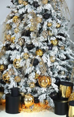 Yeni yıl ağacı, yeni yıl oyuncakları, altın ve siyah toplar ve ışıklarla süslenmiş. Hediye kutuları. Altın ve siyah. Çağdaş dekor. Noel tasarım konsepti. 