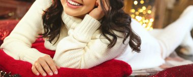 Beyaz örgü süveter ve taytlı genç ve güzel bir kadın ışıkların yanında yatıyor ve bir Noel ağacı Noel mucizelerini hayal ediyor. İç mekan. Yeni yıl ve Noel konsepti. Yakın plan.